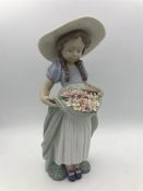 A Lladro figure of a young girl holding flowers in her dress.