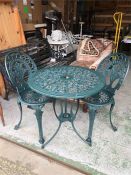 A cast iron garden table and two chairs in green