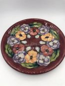 A Moorcroft 26cm plate, pansy design.