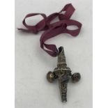 An antique silver children's rattle and whistle on a purple ribbon.