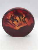 An Okra glass red paperweight with figurative design in red.