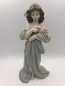 A Lladro figure of a girl with flowers in her hair.