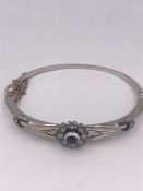 A White gold bangle with a sapphire and diamond setting