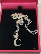 A silver initial 'C' on a silver chain cased.