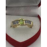 A 14ct yellow gold ring the central peridot of 60 points with 20 princess cut diamonds to the