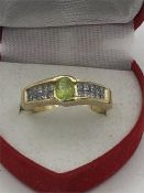 A 14ct yellow gold ring the central peridot of 60 points with 20 princess cut diamonds to the