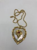 An Asian gold heart shaped pendant on an Asian gold chain