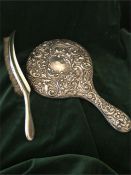A silver backed dressing table mirror and a clothes or crumb brush