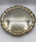 A silver salver with pie crust rim and scroll feet, hallmarked Sheffield 1954