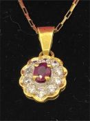 A yellow gold pendant necklace set with ruby and diamonds on gold chain.