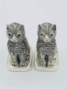 A pair of 800 silver condiments in the form of cats with emerald eyes.