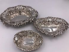 Three assorted silver pin trays with repousse design.