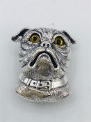 A silver dog brooch with glass eyes