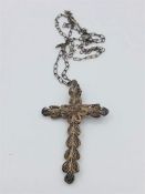 A silver filigree cross on a silver chain