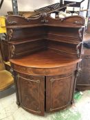 A Mahogany corner cabinet with scroll detail.