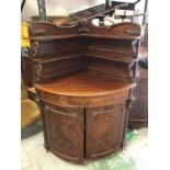 A Mahogany corner cabinet with scroll detail.