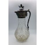 A Cut glass claret jug with white metal top with Lion finial.