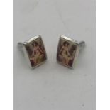 A pair of sterling silver and enamel cufflinks depicting a nude woman.
