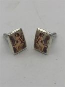 A pair of sterling silver and enamel cufflinks depicting a nude woman.