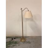 A floor standing brass reading lamp with cream shade