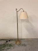 A floor standing brass reading lamp with cream shade