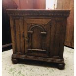 An Oak Cupboard with a notch carved cornice above a door with an arched panel on bun feet, 72 high