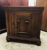 An Oak Cupboard with a notch carved cornice above a door with an arched panel on bun feet, 72 high