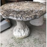 A Garden table, in stone, in a tree trunk design.