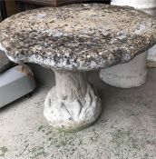 A Garden table, in stone, in a tree trunk design.