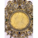 A Maria Theresa Thaler gilded in a decorative filigree mount