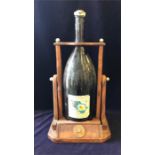 A Jeroboam of Remy Martin cognac on a wooden stand, the bottle is about a quarter full and has a