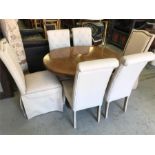 A dining table with two leaves and four cream dining chairs and two larger cream chairs.