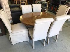 A dining table with two leaves and four cream dining chairs and two larger cream chairs.