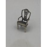 A miniature silver figure of a chair.
