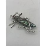 A silver plique a jour brooch in the form of a cricket set with marcasite's and rubies.