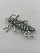 A silver plique a jour brooch in the form of a cricket set with marcasite's and rubies.