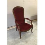A single low Victorian armchair with red velvet upholstery