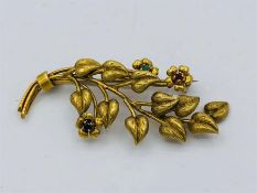 A 18ct yellow gold brooch in a branch form with emerald, ruby and sapphire stones inset for the