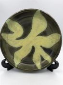 A ceramic bowl on green grounds with a floral design by Indian Artist Gulbanoo McGee, when based