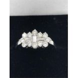An 18ct white gold Diamond ring with three baguette diamonds and twelve surrounding diamonds. Approx