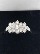 An 18ct white gold Diamond ring with three baguette diamonds and twelve surrounding diamonds. Approx