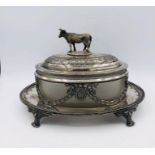 A White metal bright cut butter dish with glass loner and handle with cow finial,