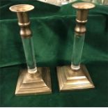 A pair of brass candlesticks with glass stems.