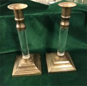 A pair of brass candlesticks with glass stems.
