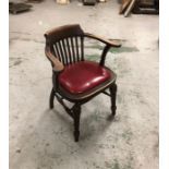 An Oak Captains chair with red seat pad.