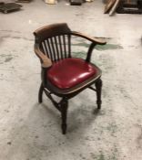 An Oak Captains chair with red seat pad.