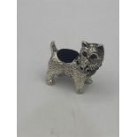 A sterling silver pincushion in the form of a dog with ruby eyes and emerald stone collar.