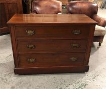 A Mahogany three drawer chest of drawers with ornate handles.