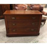 A Mahogany three drawer chest of drawers with ornate handles.