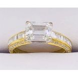 A Diamond single stone set ring with diamond set shoulders and shank sides. Emerald cut diamond